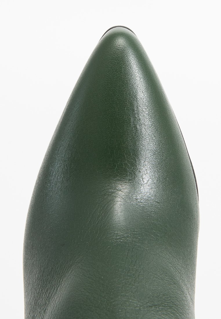 Zielony but w stylu ekoskóry z ostrym noskiem, o gładkiej fakturze i lekko błyszczącym wykończeniu. Brak widocznych elementów metalowych lub akcentów.