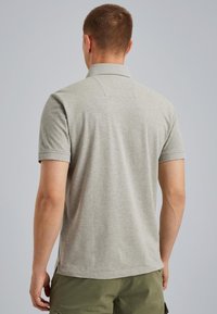 Polo gris de manga corta con dobladillo recto y cuello, hecho de un tejido suave y texturizado. La vista trasera muestra un diseño simple y un ajuste relajado.