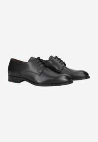 Zapatos de cuero negros con un acabado suave, puntera redondeada y costura decorativa. Cuenta con cinco ojales para los cordones y un tacón de goma bajo.