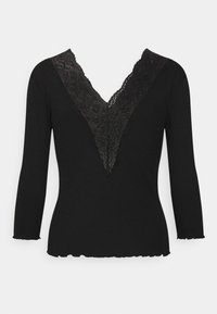 Black long-sleeve top featuring a deep V-neck with intricate lace trim. The hem has a slightly scalloped edge, complementing the textured fabric.