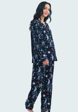 Donkerblauwe pyjama-set van zachte stof, met een hemels patroon van sterren en manen in witte, roze en rode tinten. Lange mouwen en broek.