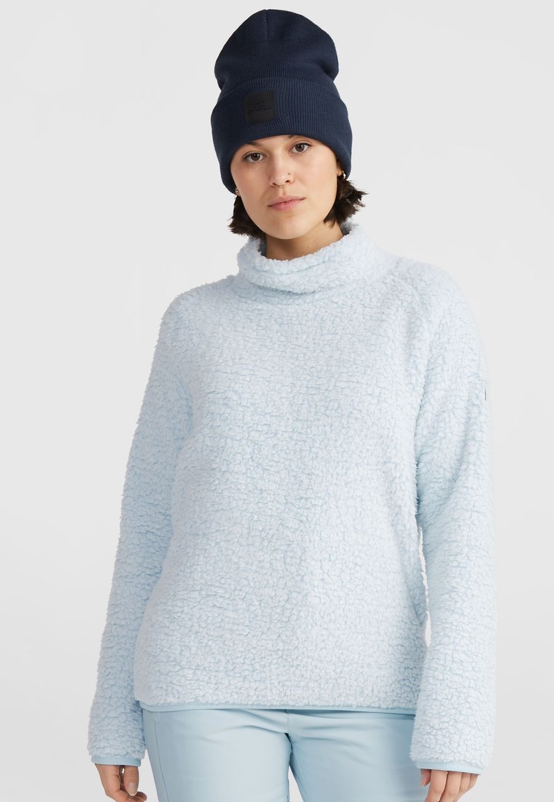Lichtblauwe fleece trui met een hoge kraag en lange mouwen, met een gestructureerd oppervlak. Gecombineerd met een donkerblauwe gebreide muts.