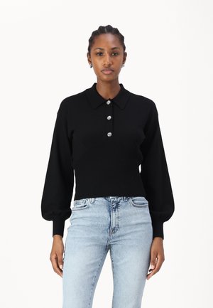 Maglione polo nero a maglia con vita a coste, patta con bottoni e maniche lunghe a sbuffo. Abbinato a jeans a vita alta blu chiaro.