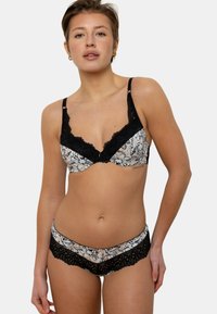 Soutien-gorge noir avec bordure en dentelle et culotte assortie, au motif floral sur un fond clair, dotés de bretelles réglables et d'une texture douce.