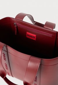 Borsa a tote rossa in pelle con due manici e una tasca interna con zip, dotata di un'etichetta rossa "HUGO".