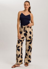Marineblauwe camisole top en beige wijde broek met een donker bloemenpatroon. De broek heeft een elastische tailleband en is gemaakt van een lichtgewicht stof.