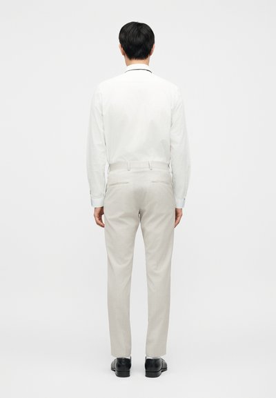 Ανοιχτόχρωμο, ραμμένο παντελόνι με ομαλή υφή και ίσια γραμμή. Συνδυάζεται με λευκό πουκάμισο με μακριά μανίκια, φορεμένο με μαύρα παπούτσια.