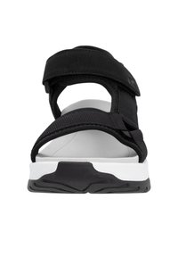 Sandale noire avec des sangles réglables en velcro, une semelle intérieure blanche rembourrée et une semelle extérieure en caoutchouc noir texturé. Design minimaliste, arrière ouvert.