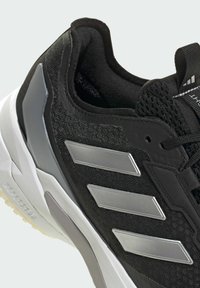 Zwart sportschoen met mesh bovenwerk en zilverkleurig ontwerp met drie strepen. Slank profiel, gevoerde kraag en gestructureerde rubberen zool voor grip.