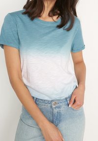 T-shirt med kort ärm med en gradientdesign som övergår från teal till vit, tillverkad av mjukt, lätt material.