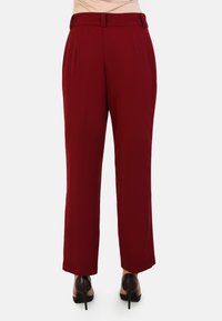 Rode hoge taille broek met een rechte snit, voorzien van riemlussen en een gladde textuur. Strakke lijnen en minimale details.