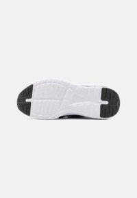 Semelle d'une chaussure de sport avec une base blanche et des patchs de grip en caoutchouc noir au niveau du talon et des orteils.