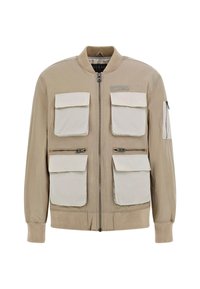Veste bombardier kaki avec quatre grandes poches avant, fermetures éclair, poignets côtelés et un col rond avec un logo sur la poitrine.