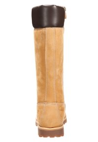Bottes en cuir beige hautes avec un revers en cuir marron, texture lisse, couture visible et semelle en caoutchouc. Présente une fermeture éclair à l'arrière.