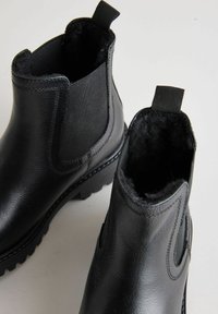 Botas de tobillo de cuero negro con un acabado texturizado, paneles laterales elásticos y pestañas para tirar, que cuentan con una suela resistente para un mejor agarre.