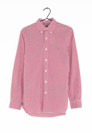 Chemise à manches longues à carreaux rouges et blancs avec col, suspendue sur un cintre noir contre un fond blanc.