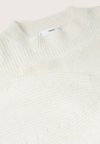 Pull en maille côtelée blanche avec col rond et étiquette de marque MNG visible à l’intérieur du col.