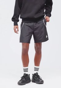 Svarte atletiske shorts med hvit piping, lette materialer og brodert logo. Saty sammen med svarte joggesko og stripete sokker.