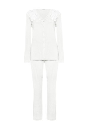 Bílý dvoudílný set domácího oblečení zahrnující košili na knoflíky s krajkovými detaily na ramenou a dlouhými rukávy, doplněný o úzké kalhoty.