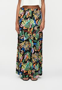 Jupe maxi florale avec des motifs de feuilles tropicales multicolores. Présente un fond noir, des boutons à la taille et un design fluide.