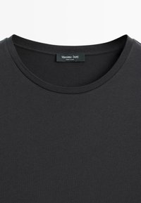 T-shirt noir à col rond avec étiquette Massimo Dutti visible cousue à l’intérieur du col, fabriqué en Chine.