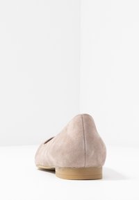 Bailarinas de ante rosa claro con punta redondeada y tacón de goma bajo y plano. La textura parece suave y lisa, mostrando un diseño minimalista.