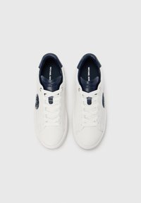 Biele tenisky s námorníckymi akcentmi, vybavené hladkým koženým zvrškom, okrúhlou špičkou, plochými šnúrkami a kruhovým logom na boku.