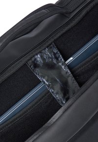 Laptop säkrad inuti ett svart vadderat fack med ett sytt tygband och dragkedjestängning på insidan av en svart väska.