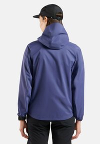 Purple waterproof jacket with a hood, elastic cuffs, and a smooth texture, worn with black shorts. Features a minimalistic design.