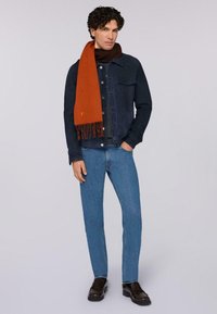 Dunkelblaue Jeansjacke, orangefarbener Schal mit Fransen, hellblaue Jeans und braune Slipper. Einfaches, modernes Design mit kontrastierenden Farben.