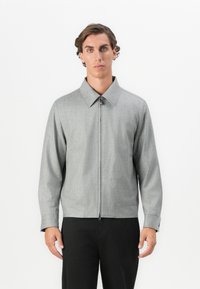 Gray zip-up jacket with a collared neckline, featuring smooth texture and side pockets, paired with black trousers.