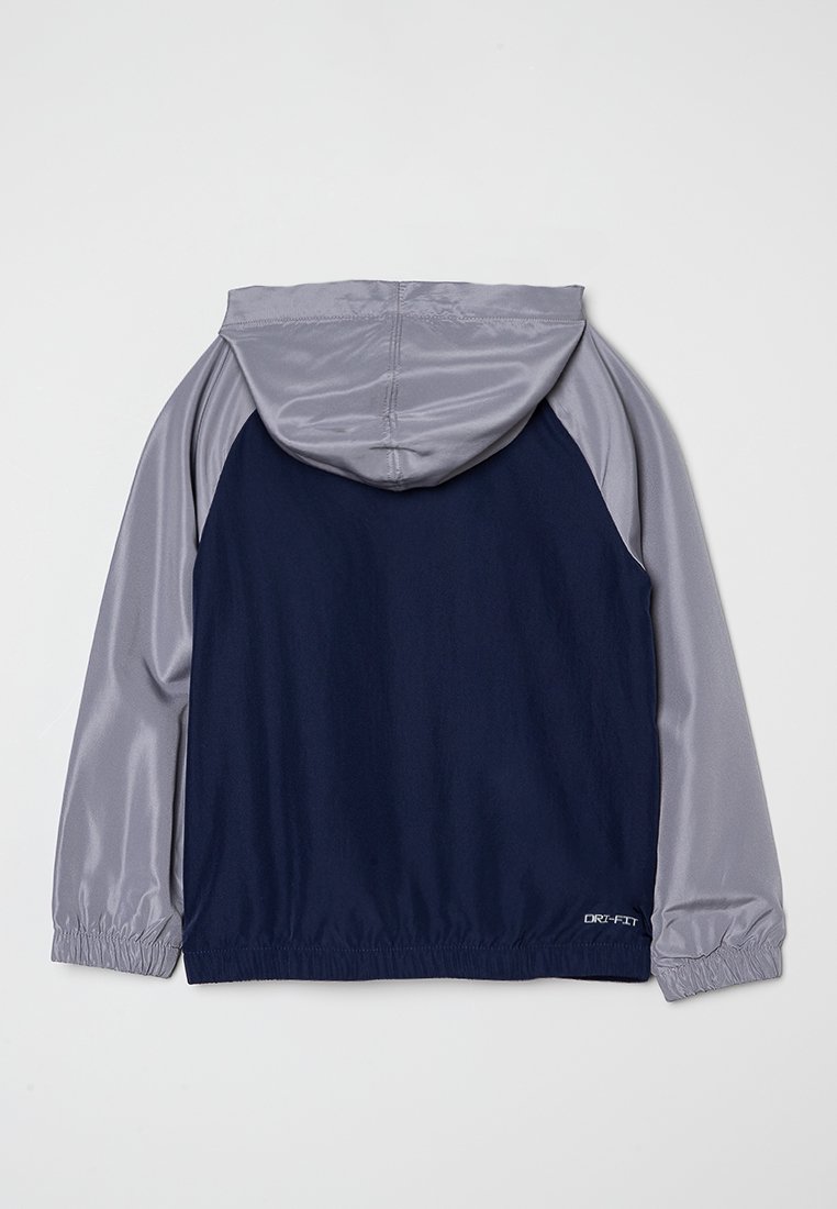 Giacca sportiva con cappuccio, corpo blu navy e maniche e cappuccio grigio chiaro lucido, polsini elasticizzati e marchio "DRI-FIT" sulla parte bassa della schiena.