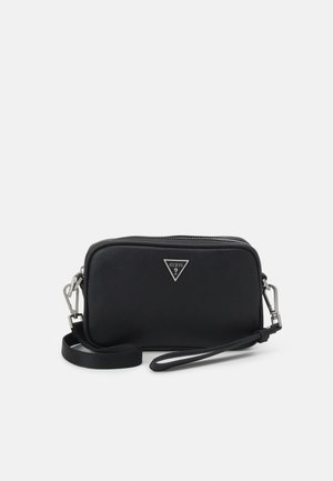Pochette noire rectangulaire avec fermeture éclair, garnitures argentées et logo triangulaire Guess au centre à l'avant.