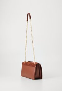 Braune Lederhandtasche mit einer strukturierten Oberseite, goldener Kettenriemen und einer klaren Form. Auffällige Details sind der Tragegriff und der Klappverschluss.