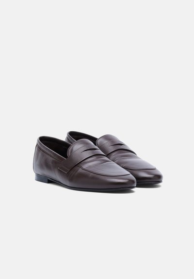 Paire de mocassins en cuir marron foncé avec un petit talon et un design classique avec bride penny, présentés légèrement en angle sur un fond blanc.