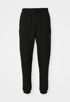 Black tapered sweatpants with elastic waistband and drawstring, side pockets, and cuffed ankles, front view.