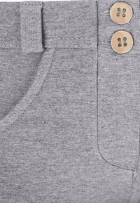 Los pantalones de algodón grises presentan una textura suave, una pretina con cierre de gancho y bucle, y dos botones decorativos beige en la parte delantera.