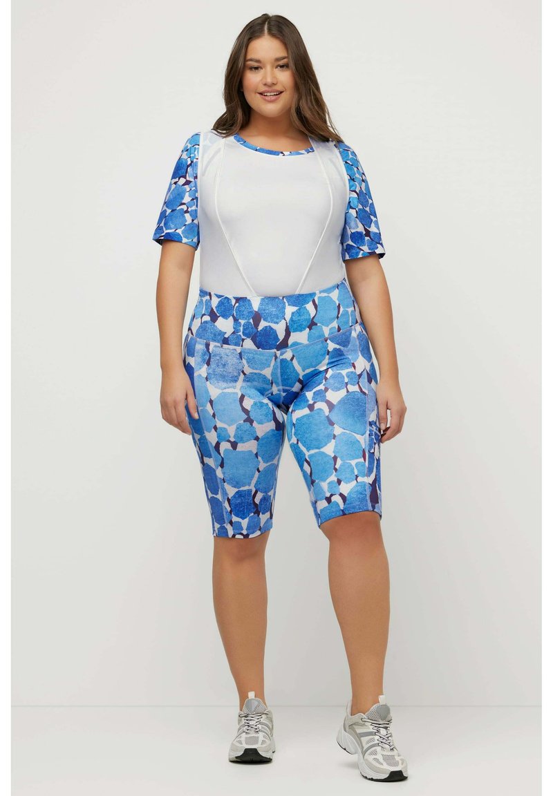 Conjunto de ropa deportiva que incluye una camiseta blanca con mangas de patrón azul y pantalones cortos de talle alto en diferentes tonos de azul con formas geométricas.