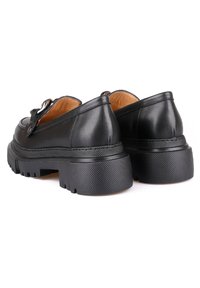 Schwarze Lederschuhe mit einer klobigen strukturierten Sohle, runder Zehenform und Metallverschlussdetail an der Seite. Glatte Oberfläche und robustes Design.
