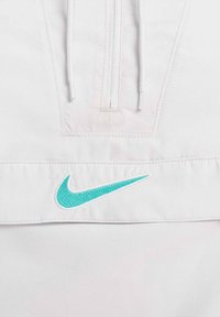 Witte lichte stof pullover met een half-rits ontwerp, met een turquoise geborduurd Nike-logo aan de voorkant.