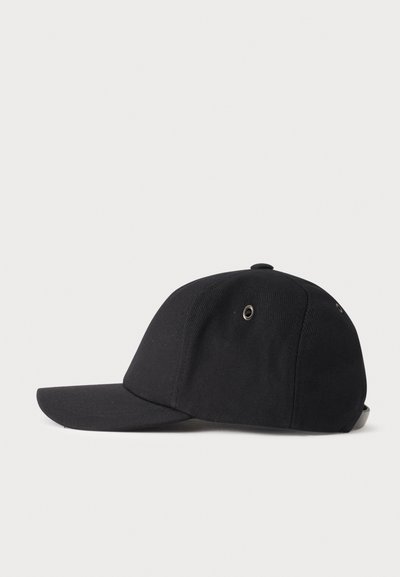 Casquette de baseball noire avec une visière incurvée et des œillets en métal, montrée de profil sur un fond clair uni.