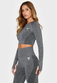 Gray athletic crop top with long sleeves, featuring a textured design and logo. Paired with high-waisted gray leggings with mesh accents.