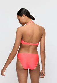 Koralowo-różowy bikini z topem na szyję z teksturowaną opaską i dopasowanymi majtkami z niskim stanem. Gładki materiał o dopasowanym kroju.