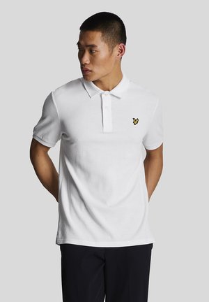Hvid polo-shirt med et struktureret stof, der har en tre-knaps placket og et lille gult fuglelogo på venstre bryst.