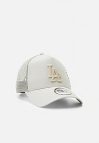 Light beige trucker cap with mesh sides, featuring a raised LA logo in matching color. Curved brim and adjustable snapback closure.