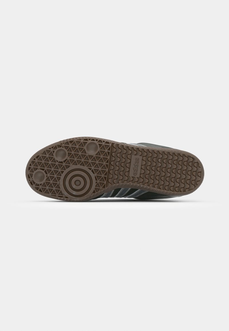 Semelle de sneaker noire et grise avec une surface en caoutchouc texturé, comportant un design circulaire et plusieurs motifs de grip pour une meilleure adhérence.