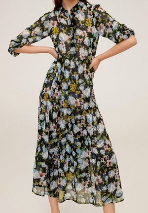 Robe midi noire transparente avec imprimé floral bleu pastel, rose et jaune, manches longues retroussées, boutonnage devant et taille froncée.