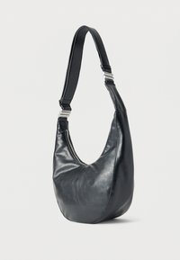 Μαύρη δερμάτινη τσάντα ώμου με φαρδιά λουράκι και ασημί αγκράφες, στρογγυλεμένος πάτος και κλείσιμο με φερμουάρ κατά μήκος της επάνω άκρης.