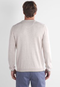 Pull gris clair à col rond et manches longues. Fabriqué en tissu doux et texturé, il présente des poignets et un ourlet côtelés.