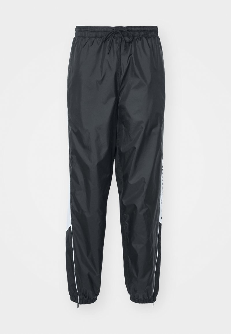 Pantalons en noir imperméables avec une taille élastique à cordon de serrage, des poignets fuselés et des poches latérales présentant des accents et un logo blancs.